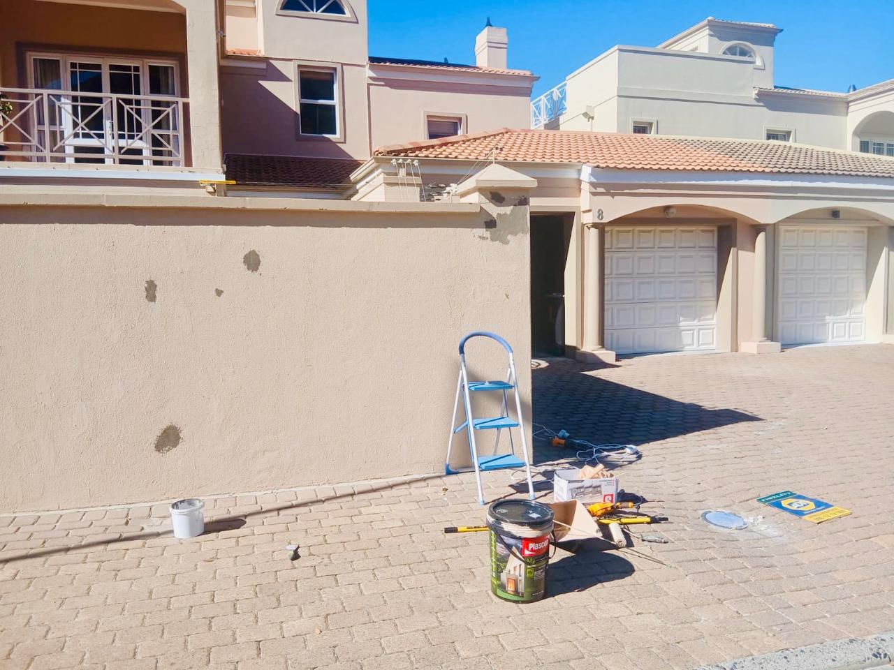 Exterior wall preparation with patched areas and painting equipment